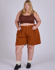 Juliet is wearing Pleated Trouser Shorts in Burnt Terracotta and fudgesicle brown Mini Tank 