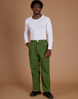 Isaac is wearing Railroad Denim Work Pants in Gross Green Overdye and vintage tee white Long Sleeve Baby Tee