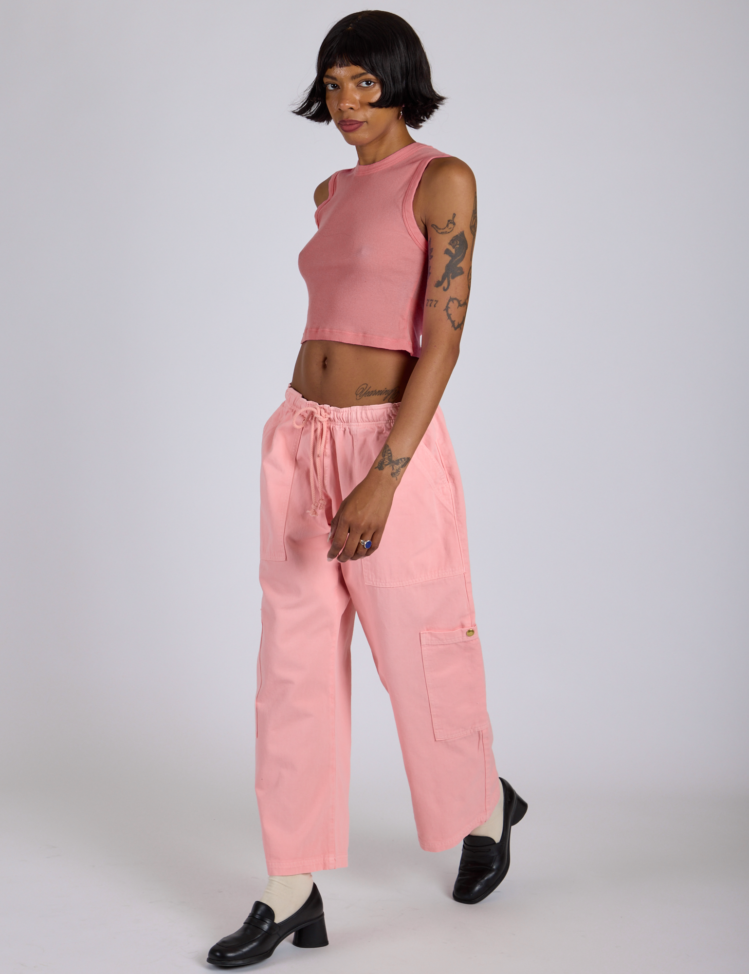 Angled front view of Drop Pocket Cargo Pants in Baby Pink and matching Muscle Tee on Kira