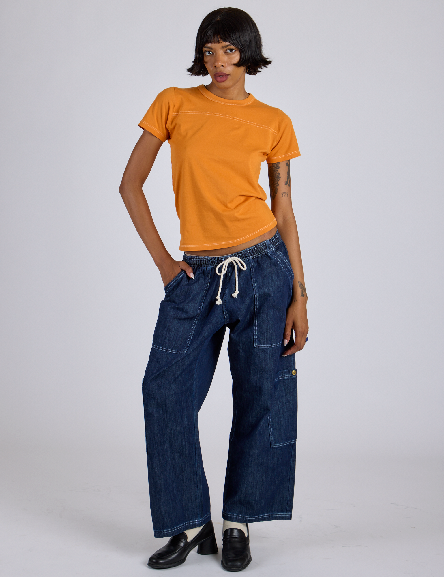 Kira is wearing Jr. Varsity Tee in Creamsicle Orange and dark wash Denim Drop Pocket Pants