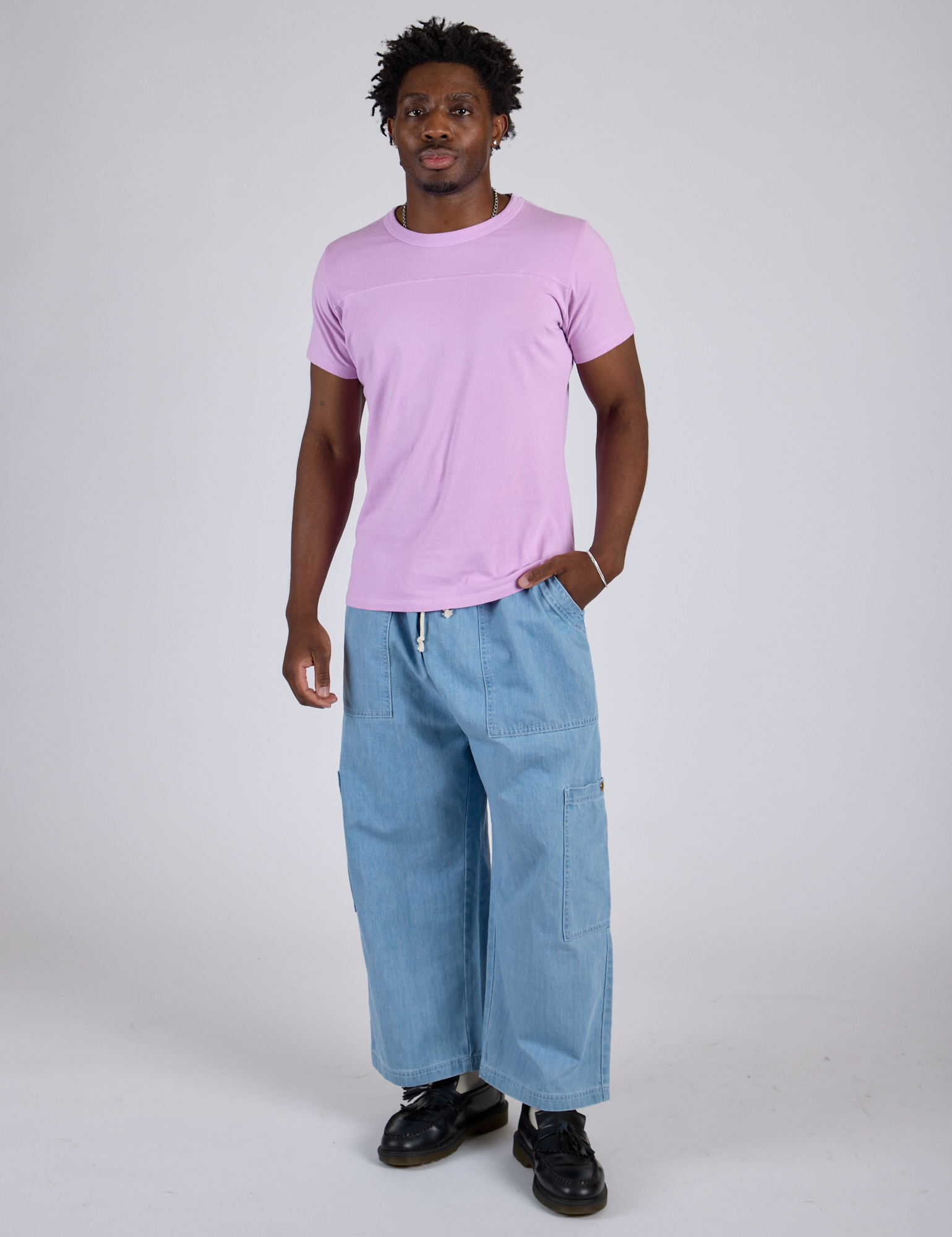 Isaac is wearing Jr. Varsity Tee in Lilac Purple and light wash Denim Drop Pocket Pants