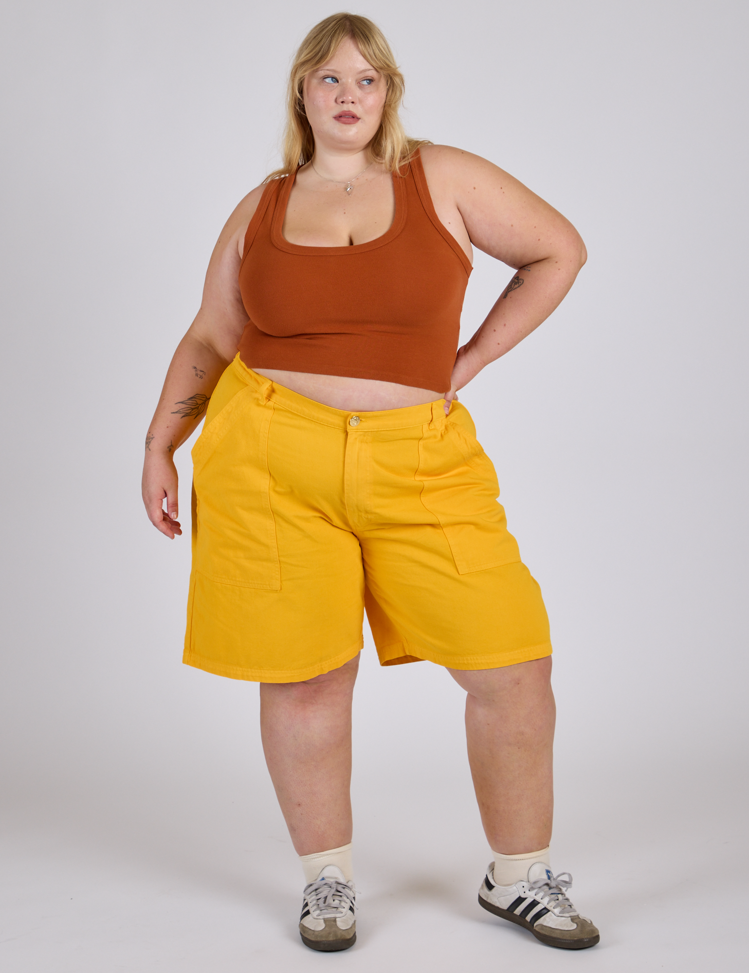 Juliet is wearing Longline Work Shorts in Sunshine Yellow and burnt terracotta Cropped Tank