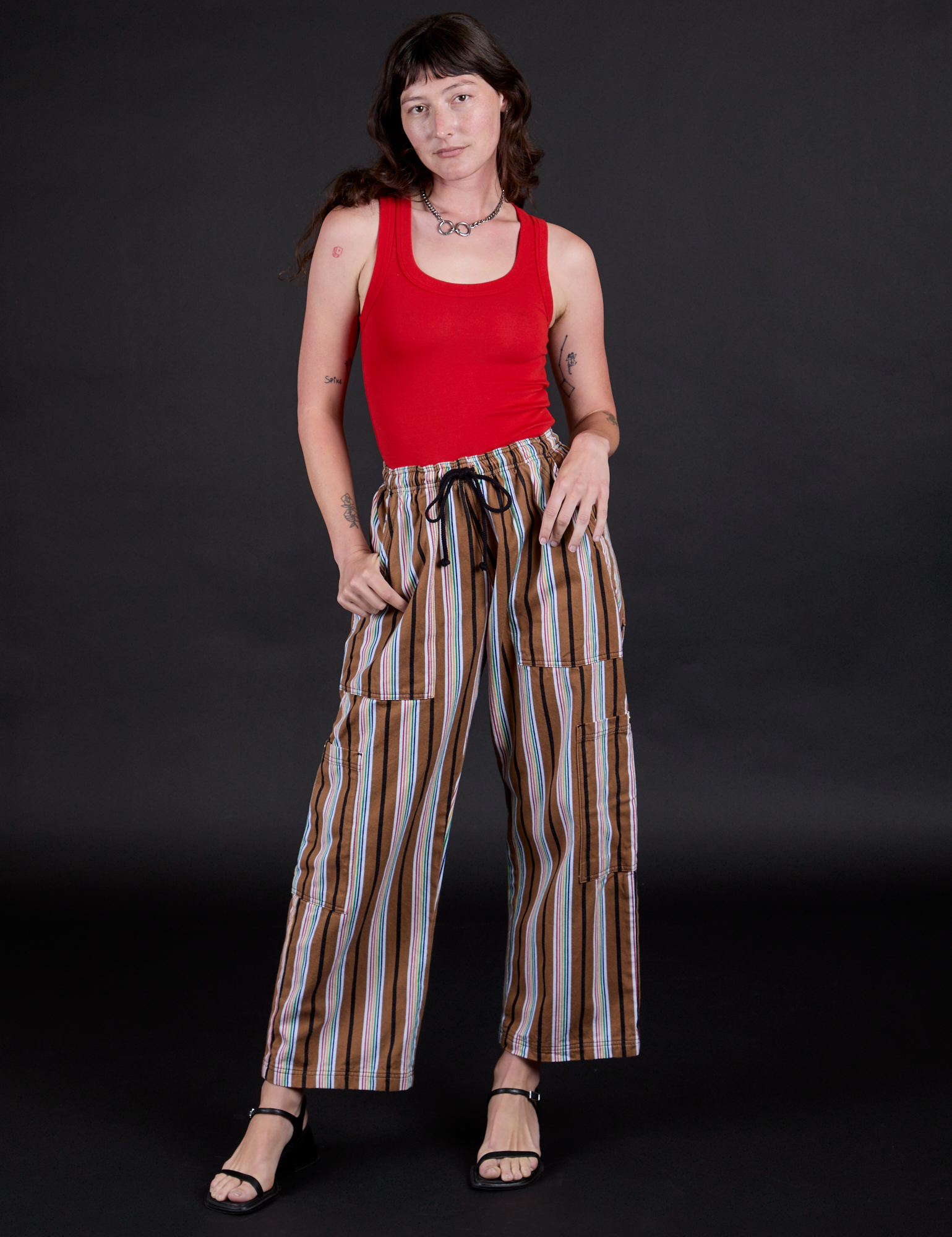Alex is wearing Striped Drop Pocket Pants in Retro Rainbow and mustang red Tank Top