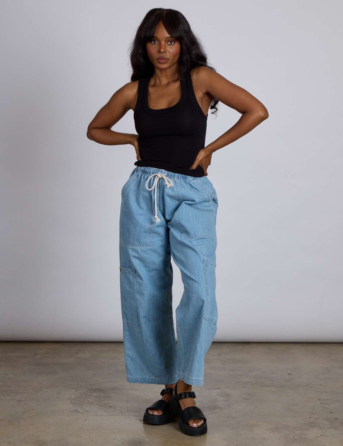 Kandia is wearing The Tank Top in Basic Black and light wash denim drop pocket pants