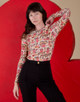 Alex is wearing Long Sleeve Baby Tee in Hot Stuff Print tucked into black Western Pants