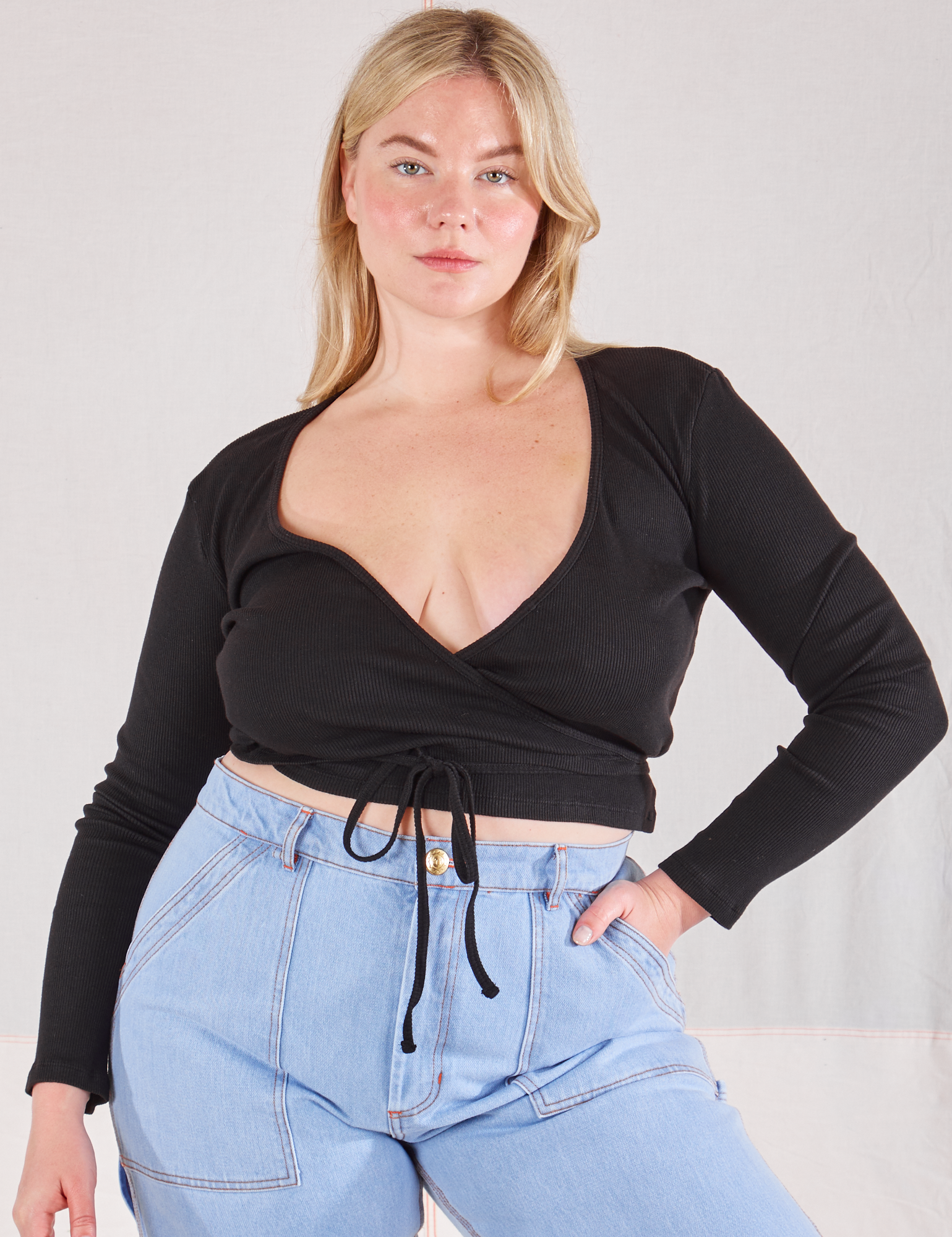 Lish is wearing Wrap Top in Basic Black and light wash Carpenter Jeans