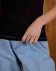 Close up of Alex holding the bottom hem of Calypso Tee in Black Multi