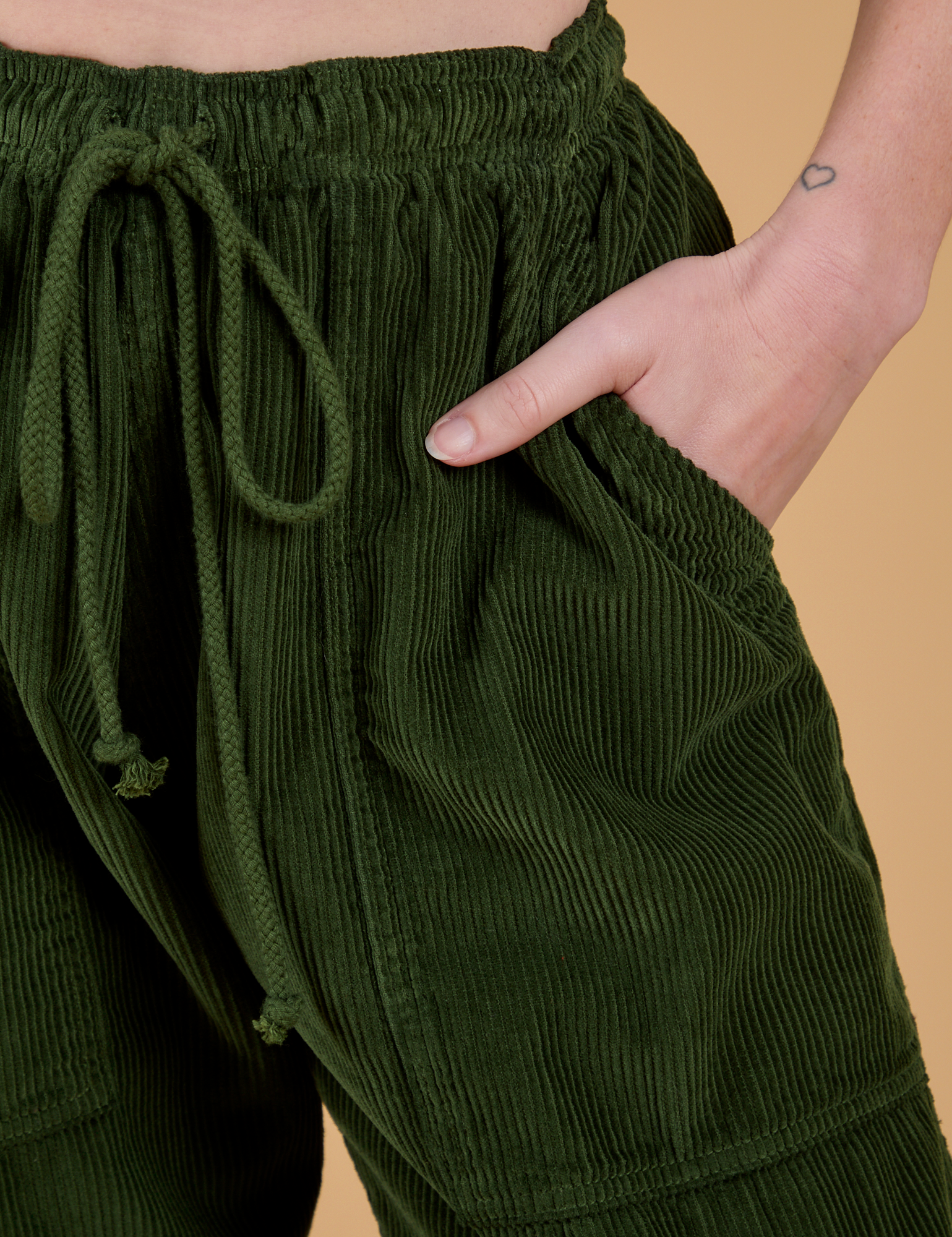 Close up of Alex's hand in the front pocket of Corduroy Drop Pocket Cargo Pants in Evergreen