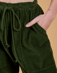 Close up of Alex's hand in the front pocket of Corduroy Drop Pocket Cargo Pants in Evergreen