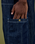 Close up of Isaac's hand in the side pant leg pocket of Denim Drop Pocket Pants in Dark Wash