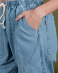 Close up of Alex's hand in the front pocket of Denim Drop Pocket Pants in Light Wash