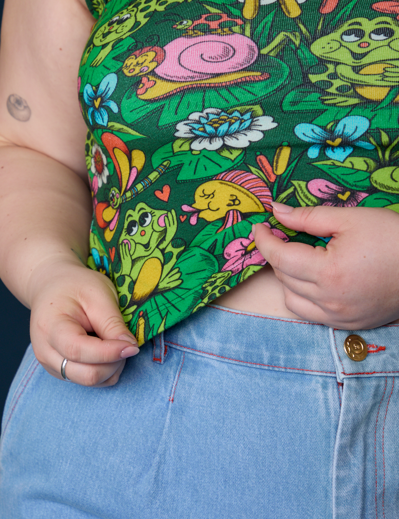 Close up of Ashley holding the hem of Cropped Tank Top in Pond Party