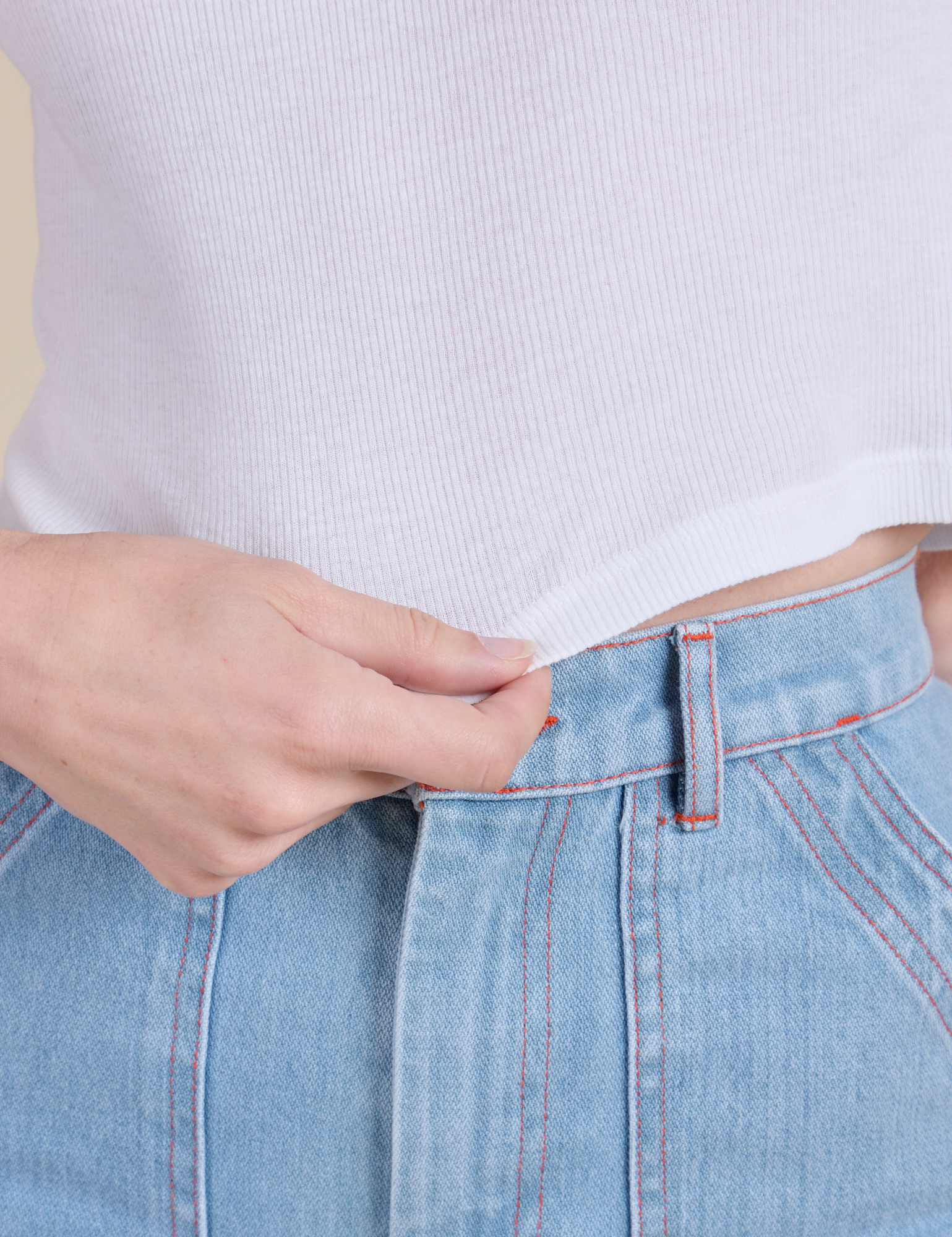 Close up of Alex holding the bottom hem of Muscle Tee in Vintage Tee White