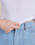 Close up of Alex holding the bottom hem of Muscle Tee in Vintage Tee White