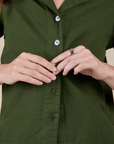 Alex is buttoning up the Pantry Button-Up in Evergreen