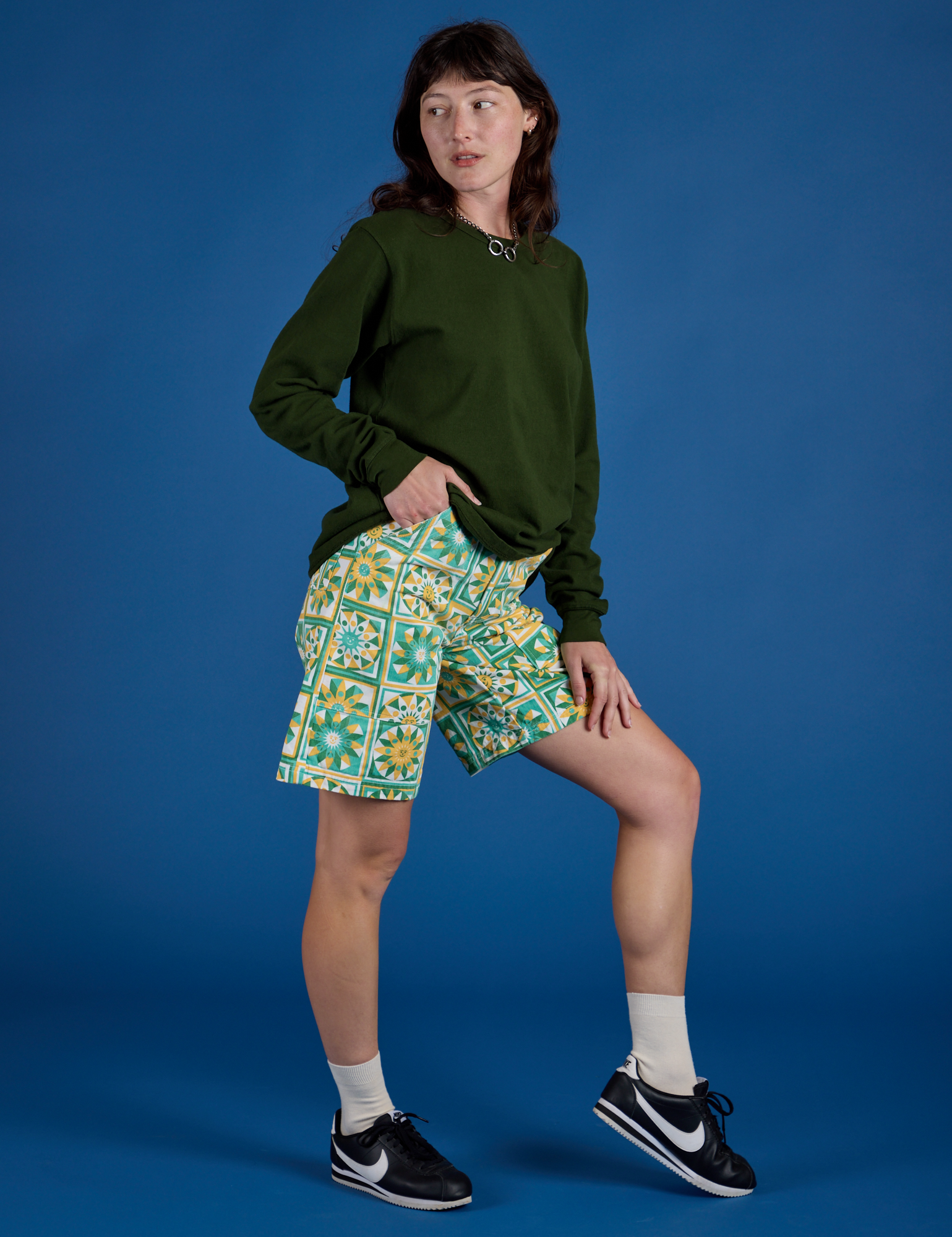 Side view of Longline Work Shorts in Spring Quilt Print and evergreen Long Sleeve Burly Tee on Alex