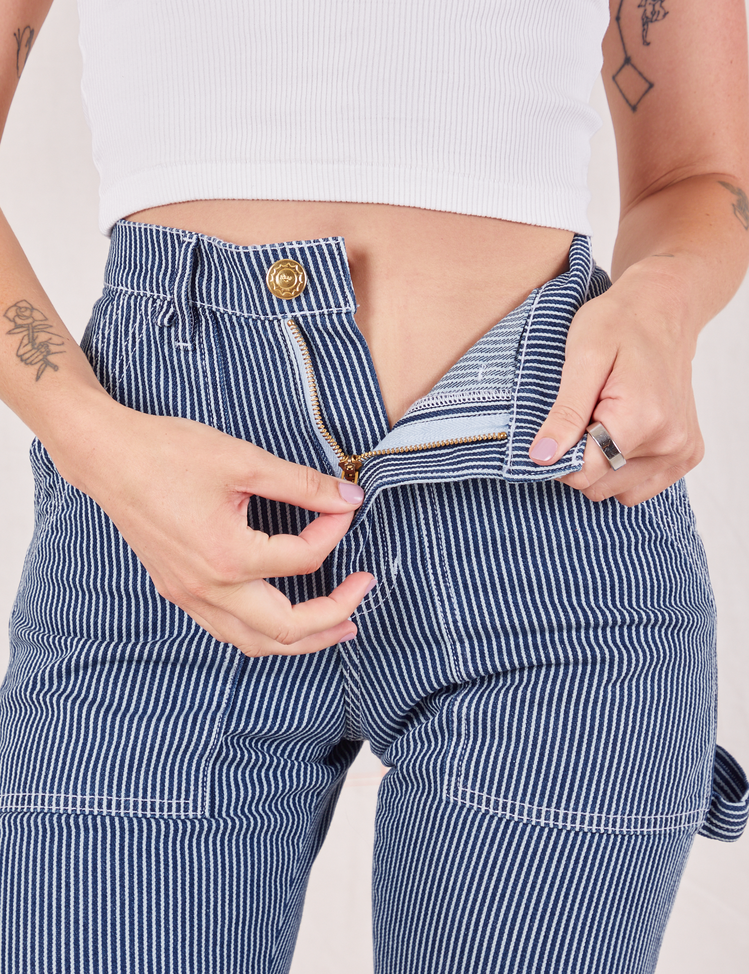 Carpenter Jeans in Indigo Railroad front close up. Alex is pulling on the zipper tab.