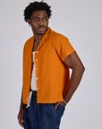 Angled front view of Pantry Button-Up in Creamsicle Orange on Isaac