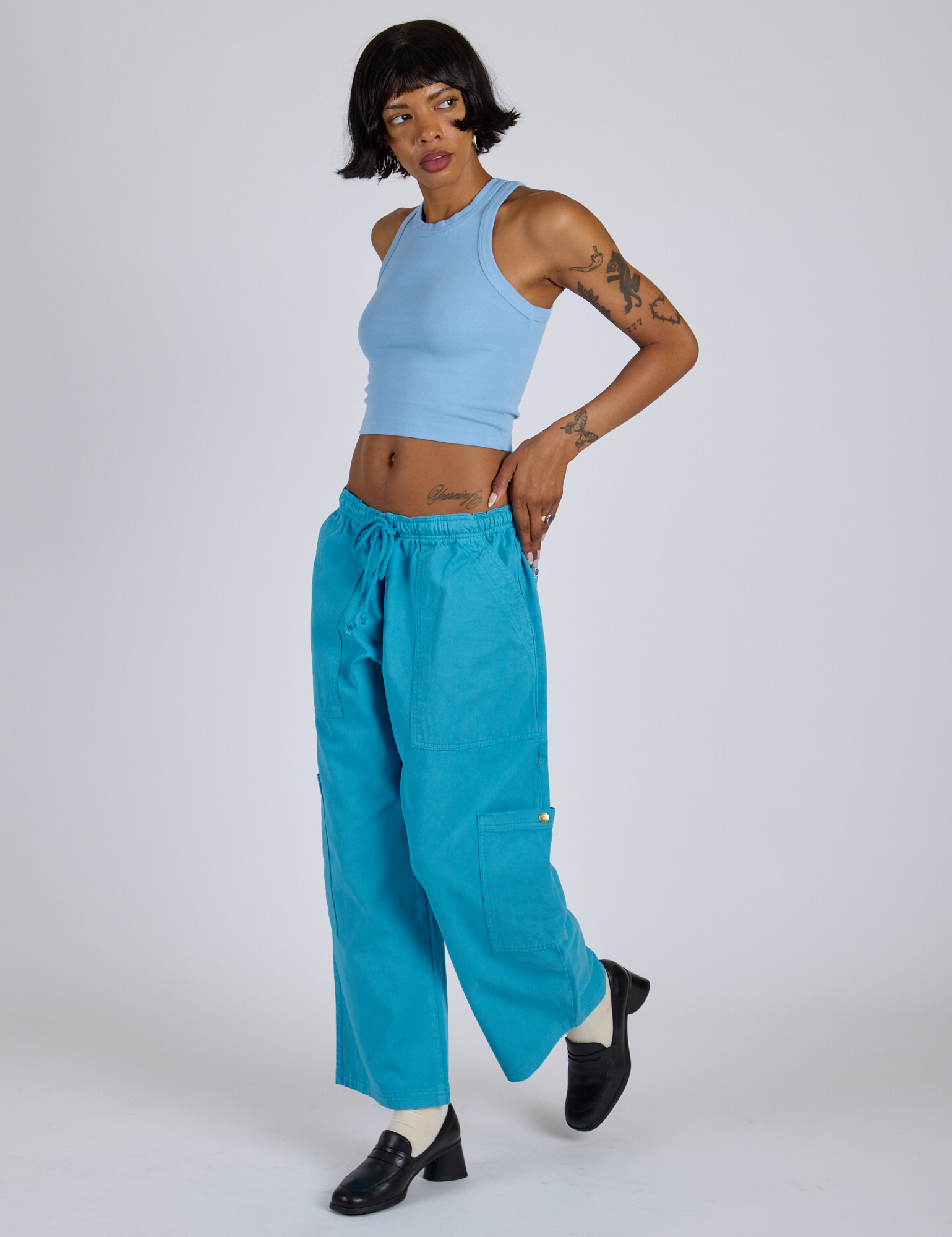 Angled front view of Drop Pocket Cargo Pants in Hawaiian Blue and baby blue Racerback Tank on Kira
