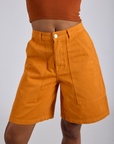 Longline Work Shorts in Creamsicle Orange close up on Kira