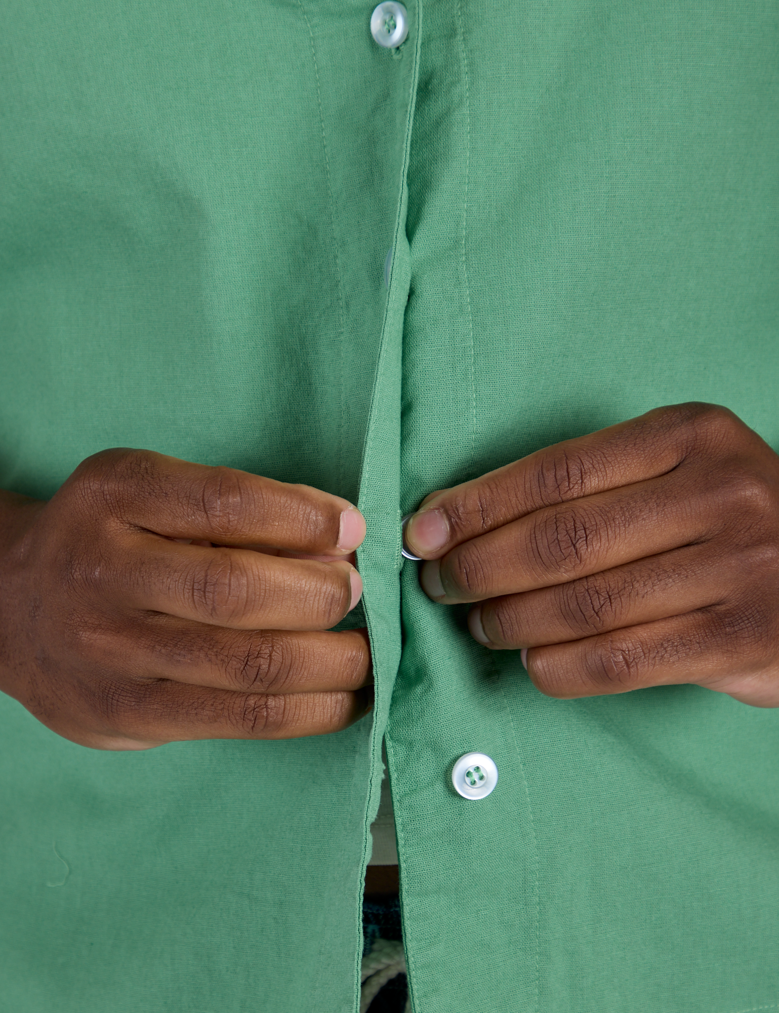 Close up of Isaac buttoning up the Pantry Button-Up in Seafoam Green