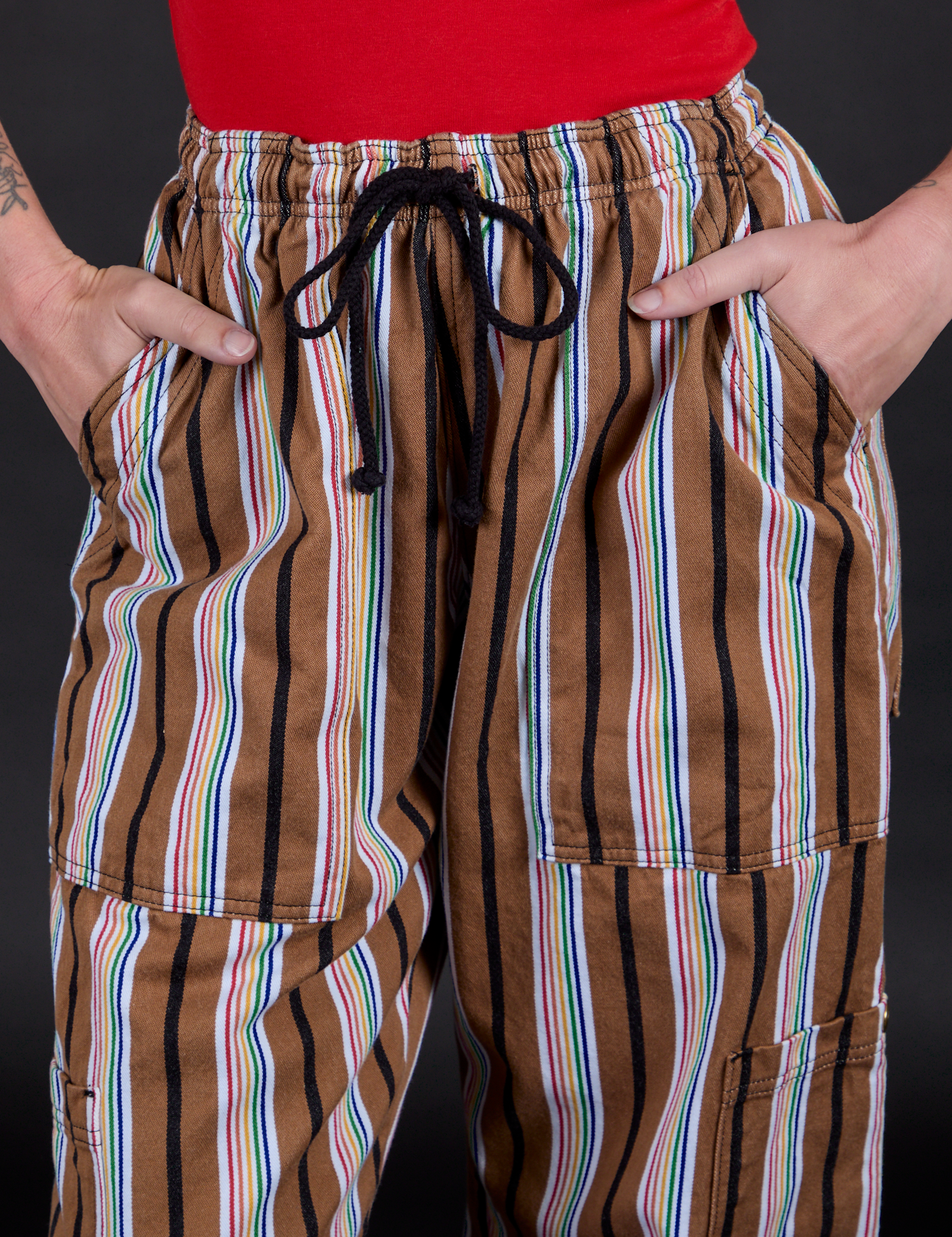 Striped Drop Pocket Pants in Retro Rainbow front close up with Alex's hand in both pockets