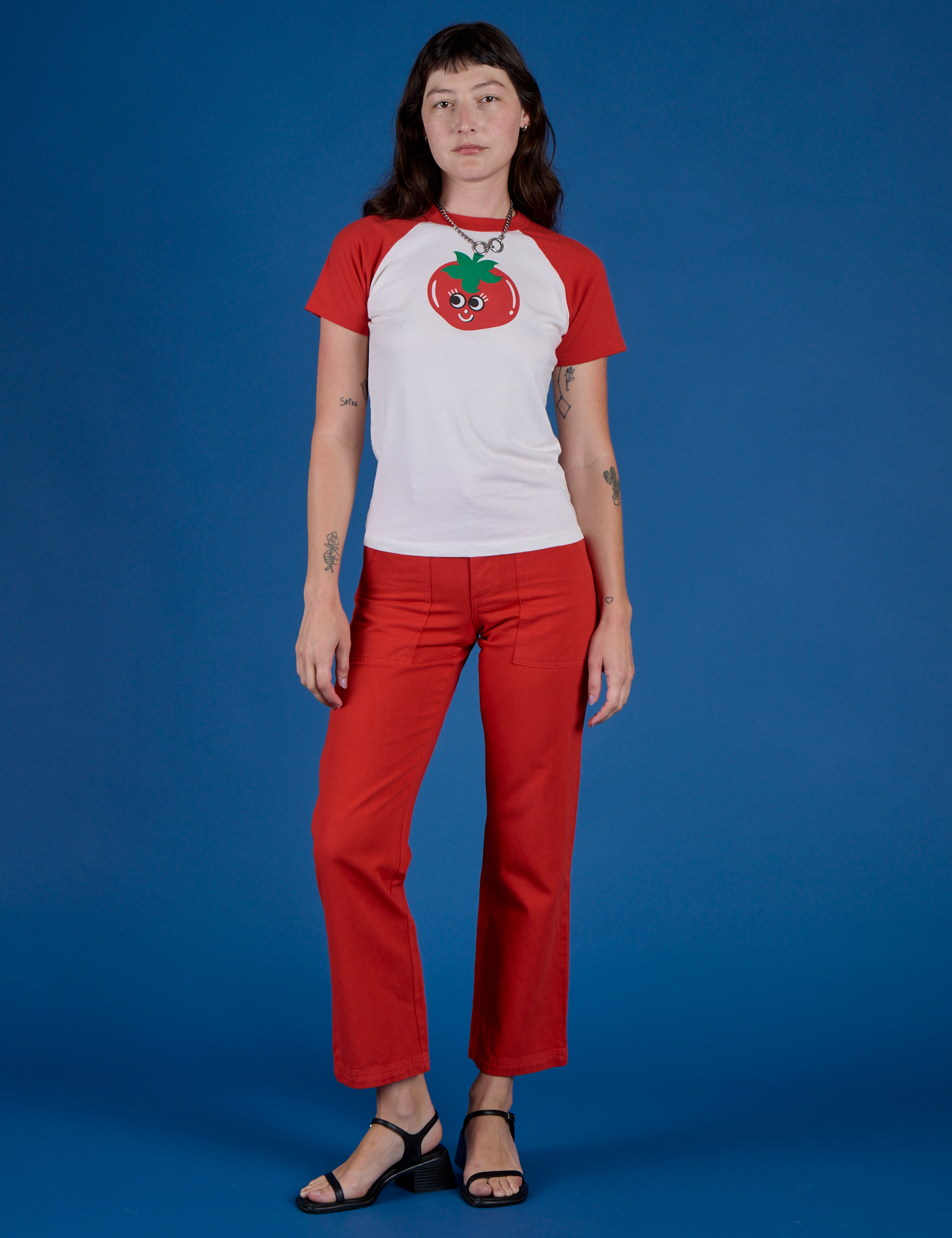 Alex is wearing Produce Raglan Tee in Tomato and mustang red work pants