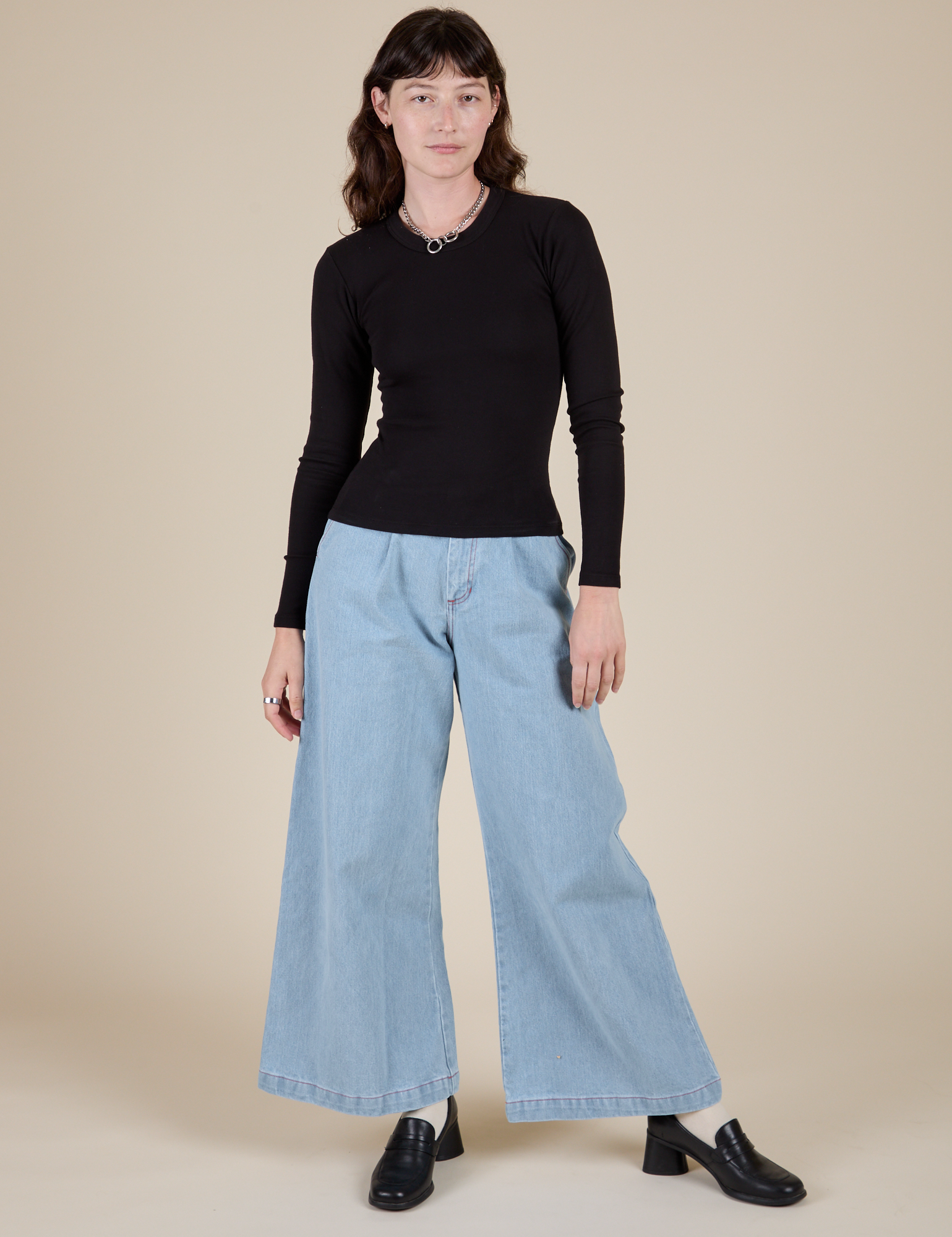 Alex is wearing Long Sleeve Baby Tee in Basic Black paired with light wash Wide Leg Trousers