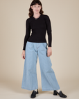 Alex is wearing Long Sleeve Baby Tee in Basic Black paired with light wash Wide Leg Trousers