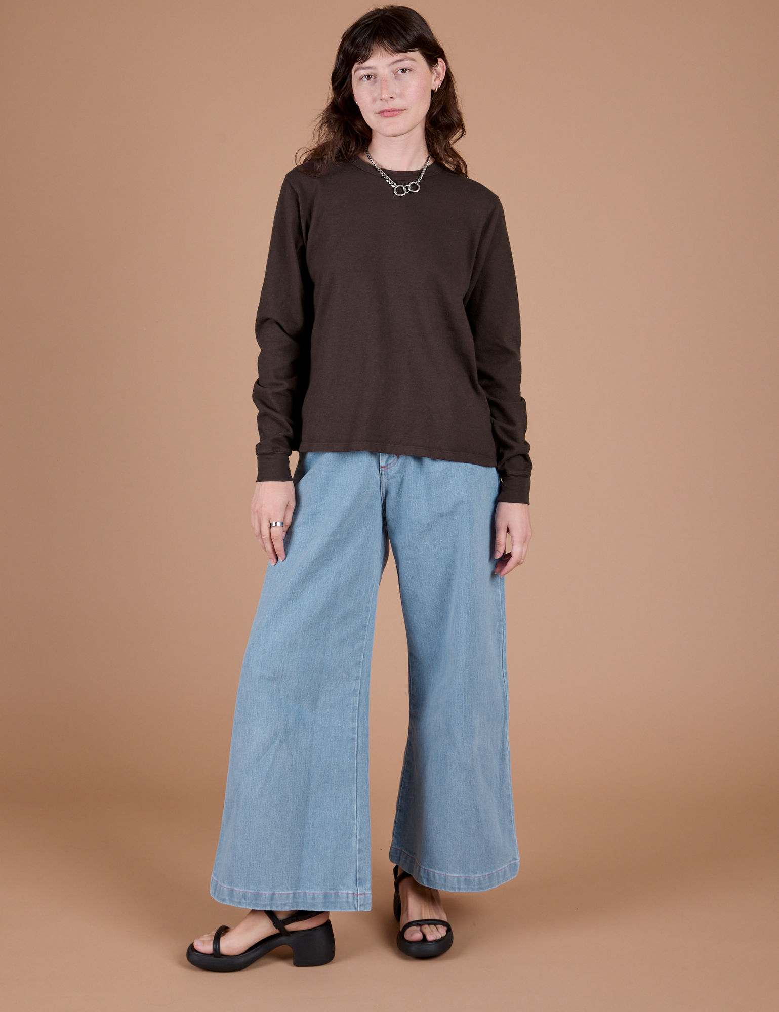 Alex is wearing Long Sleeve Burly Tee in Espresso Brown paired with light wash Indigo Wide Leg Trousers
