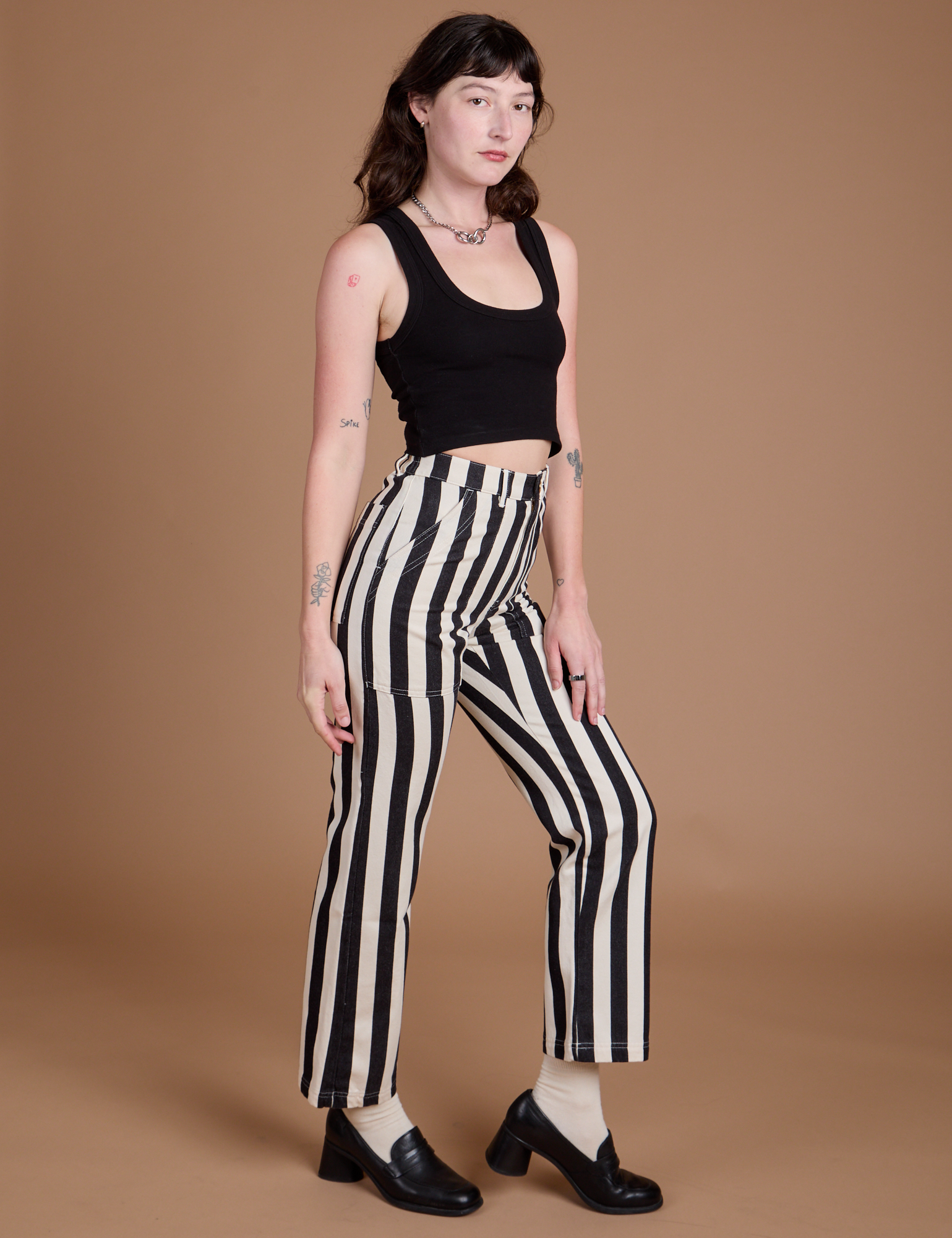 Side view of Black Stripe Work Pants in White and black Cropped Tank on Alex