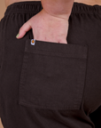 Close up of Juliet's hand in the back pocket of Action Pants in Espresso Brown