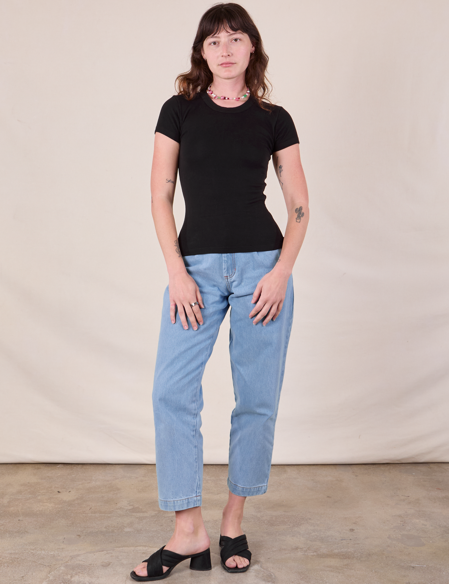 Alex is wearing Baby Tee in Vintage Basic Black and light wash Trouser Jeans