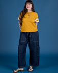 Sydney is wearing Painted Burly Tee in Mustard Yellow and denim Drop Pocket Cargo Pants