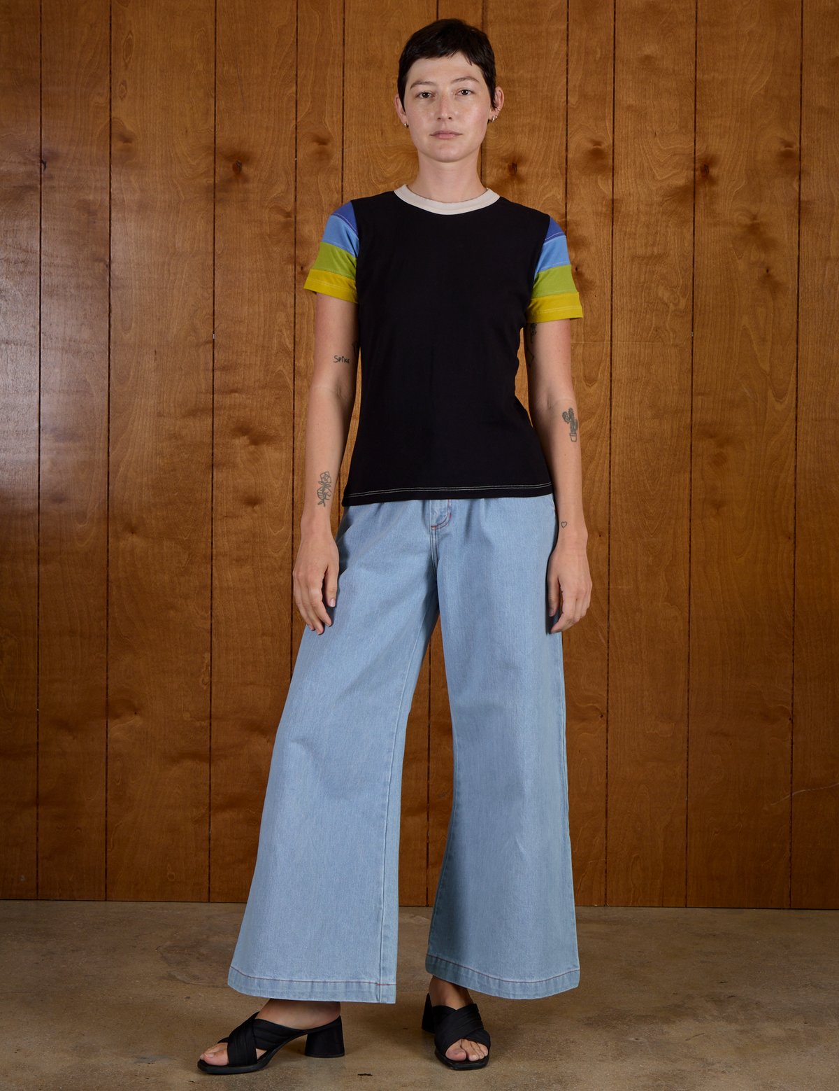 Alex is wearing Calypso Tee in Black Multi and light wash denim wide leg trousers