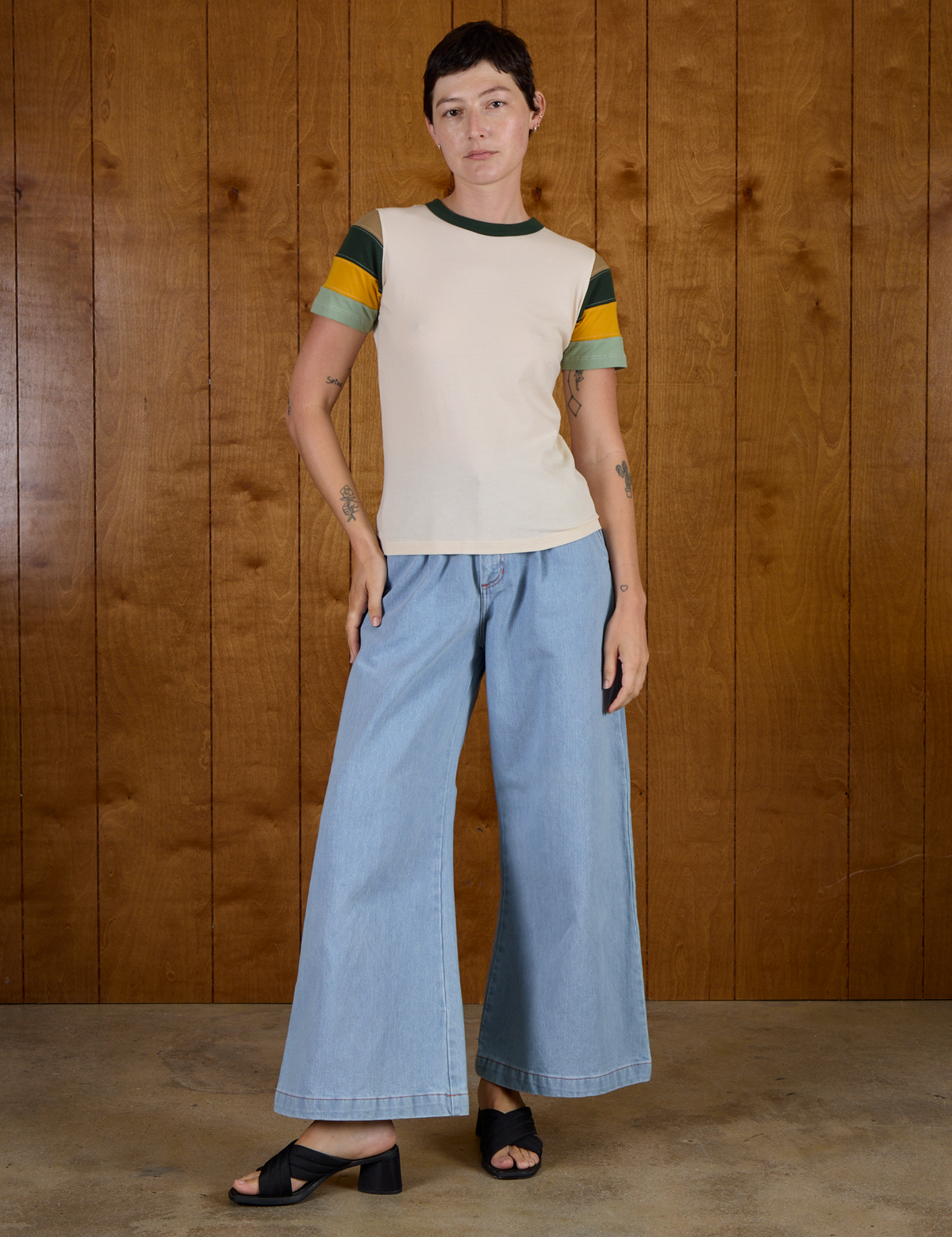Alex is wearing Calypso Tee in Off White Multi and light wash Denim Wide Leg Trousers