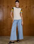 Alex is wearing Calypso Tee in Off White Multi and light wash Denim Wide Leg Trousers