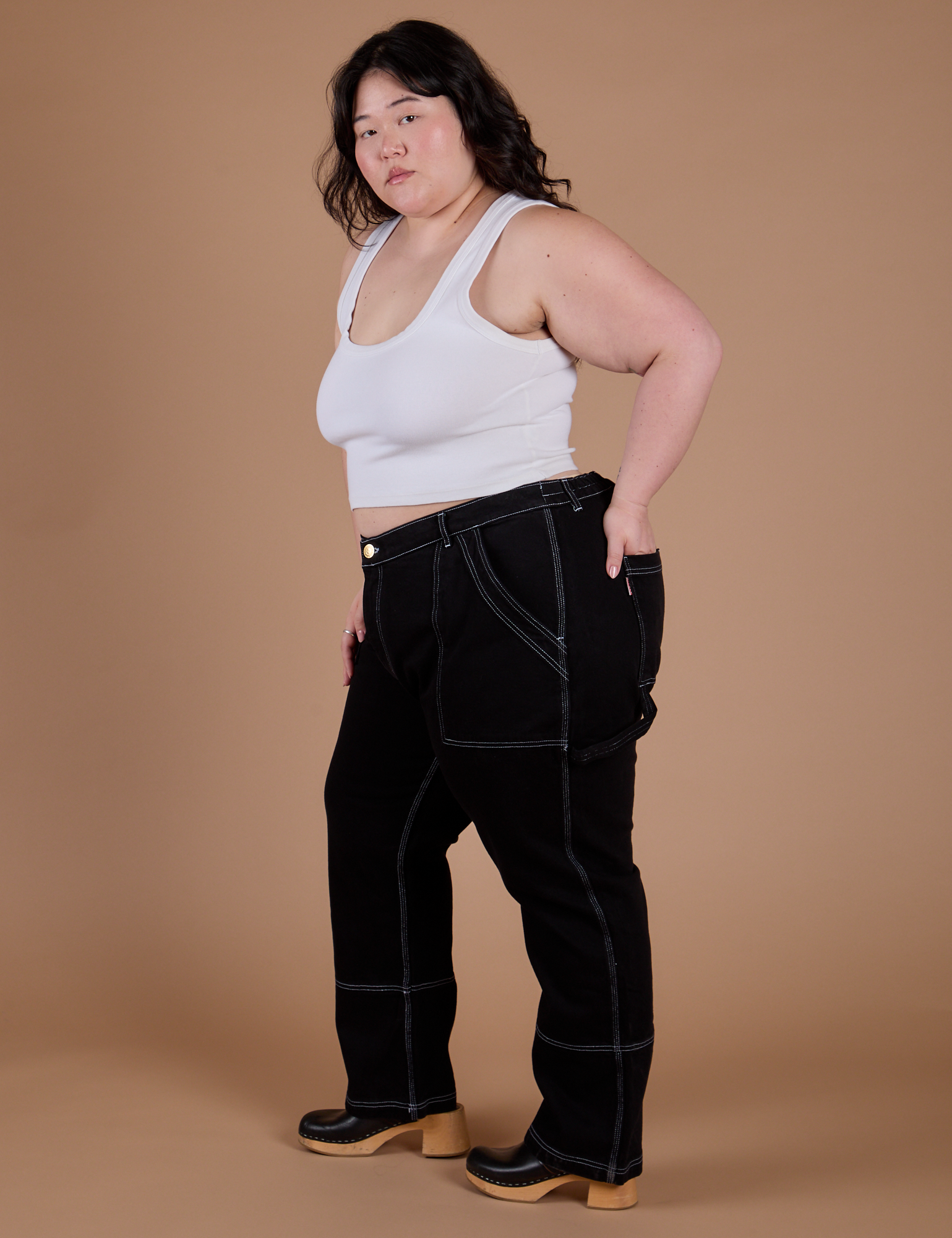 Side view of Carpenter Jeans in Black and Cropped Tank in Vintage Tee White on Ashley