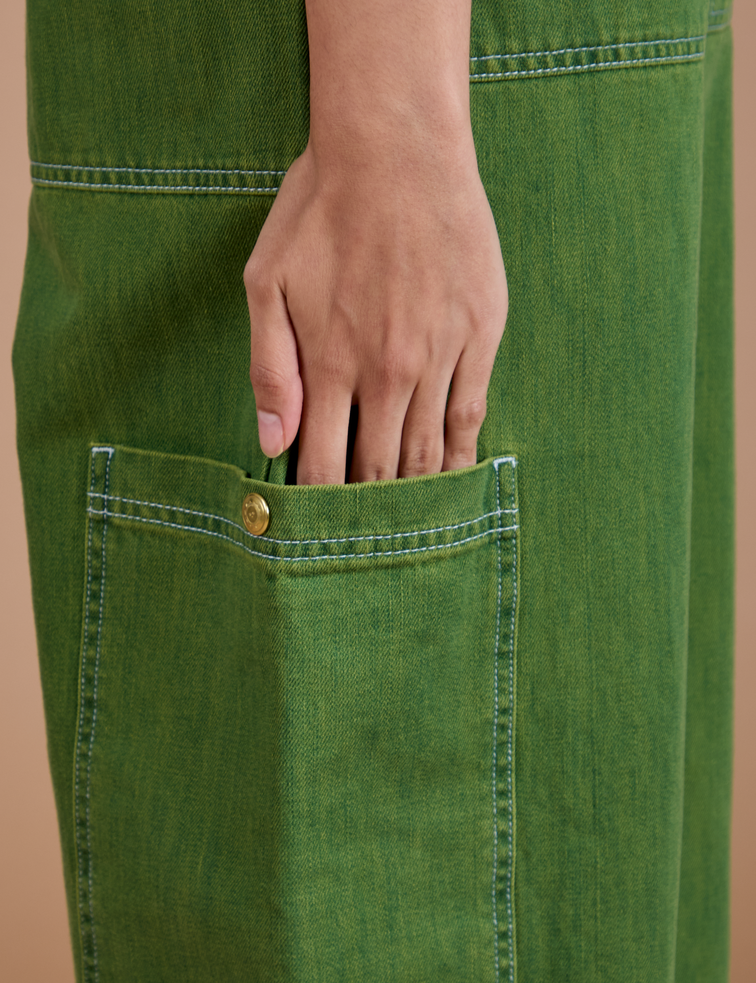 Anjaline has her hand on the side pant pocket of Denim Drop Pocket Pants in Green Overdye