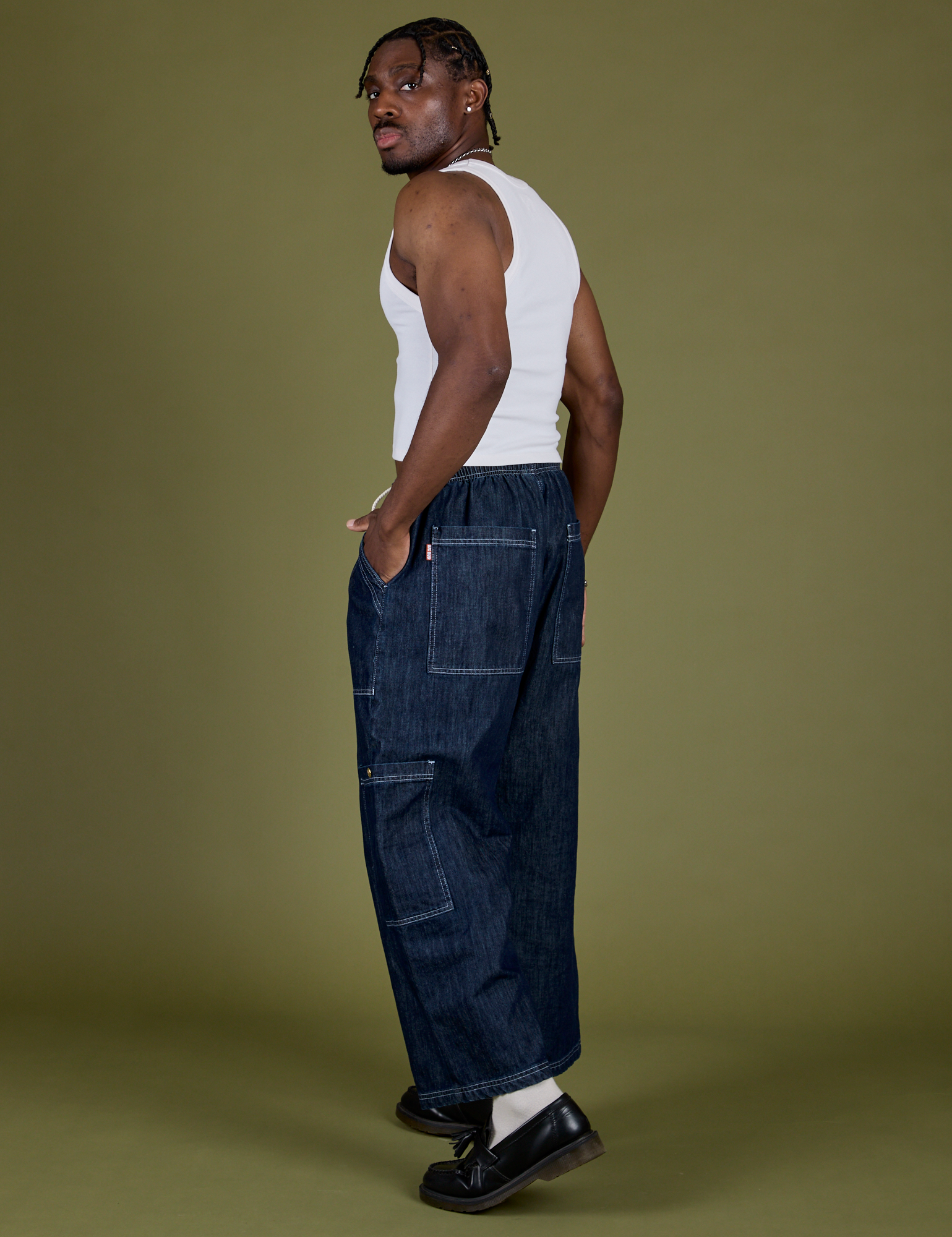 Angled back view of Denim Drop Pocket Pants in Dark Wash and vintage tee white Cropped Tank on Isaac