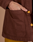 Close up of Jesse's hand in the front pocket of Ripstop Field Coat in Fudgesicle Brown