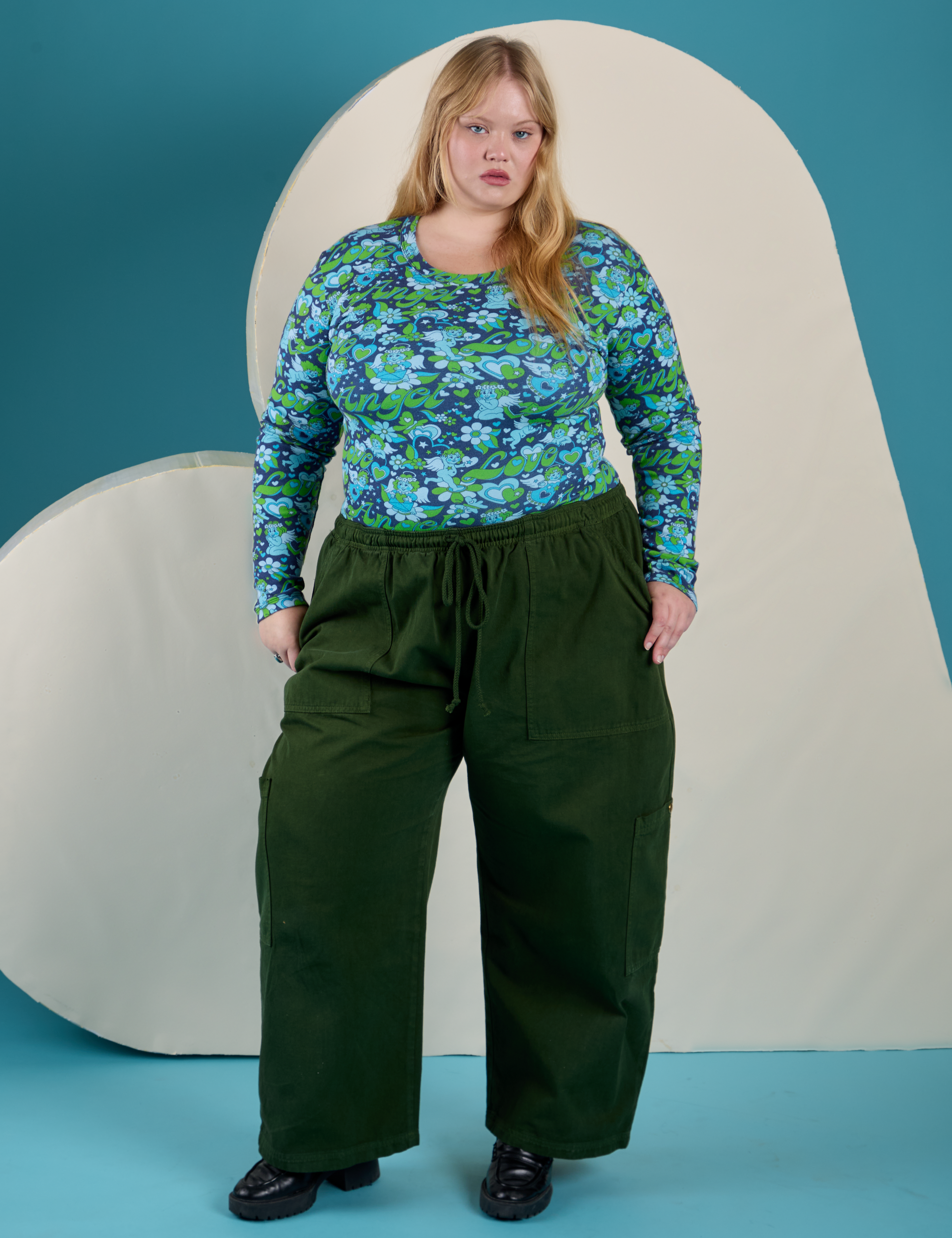 Juliet is wearing Long Sleeve Baby Tee in Angel Print tucked into evergreen Drop Pocket Cargo Pants