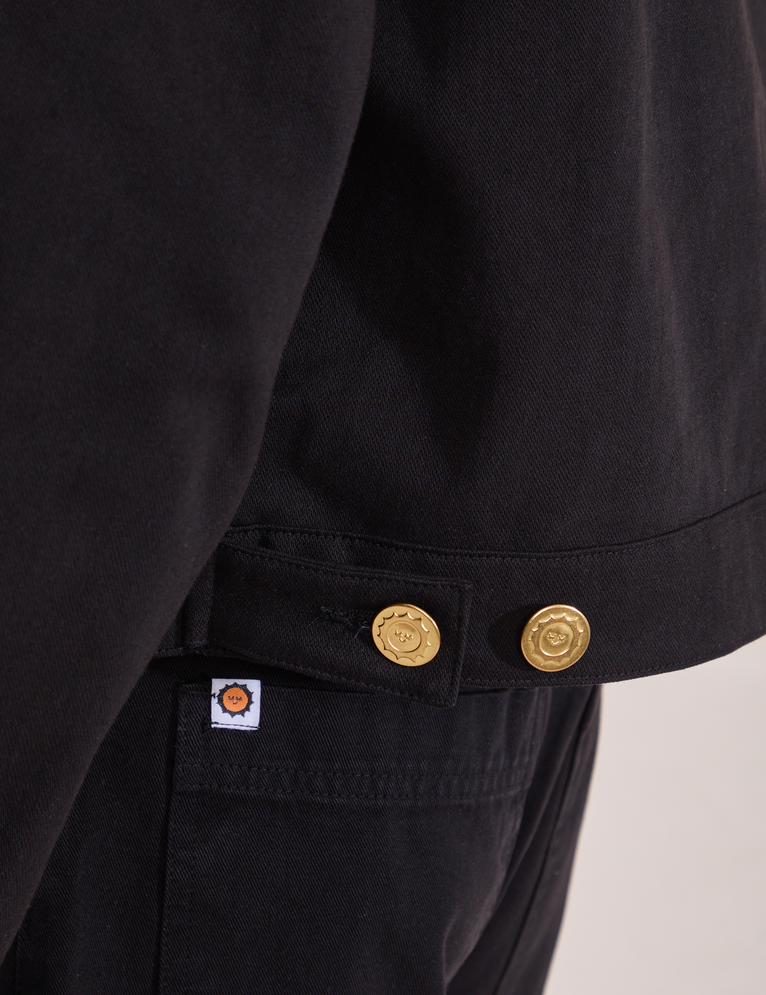 Close up of custom brass button snaps on the Mechanic Jacket in Basic Black