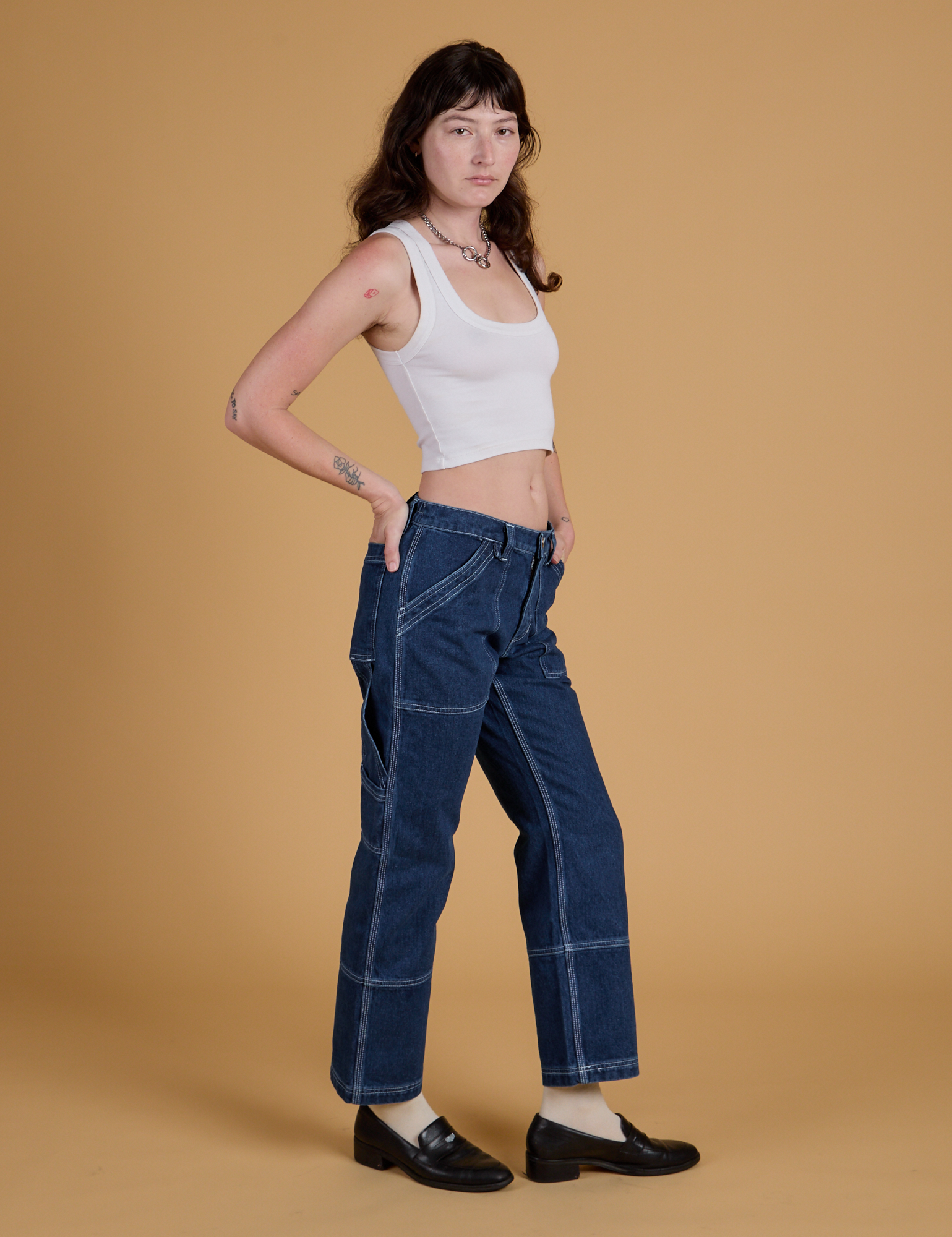 Side view of Mid-Rise Carpenter Jeans in Dark Wash and Cropped Tank in Vintage Tee White on Alex
