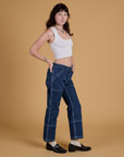 Side view of Mid-Rise Carpenter Jeans in Dark Wash and Cropped Tank in Vintage Tee White on Alex