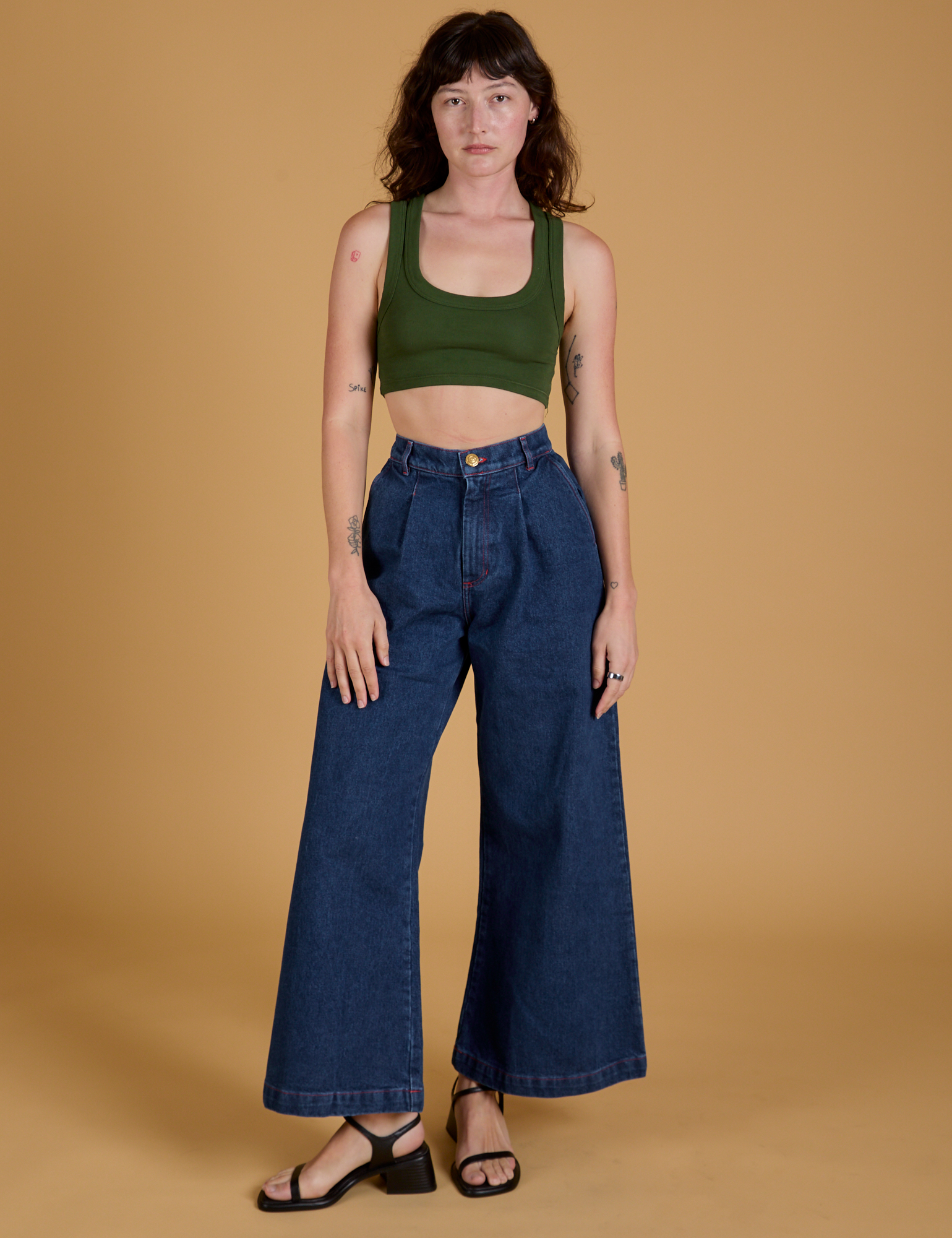 Alex is wearing Mini Tank in Evergreen and dark wash Indigo Wide Leg Trousers