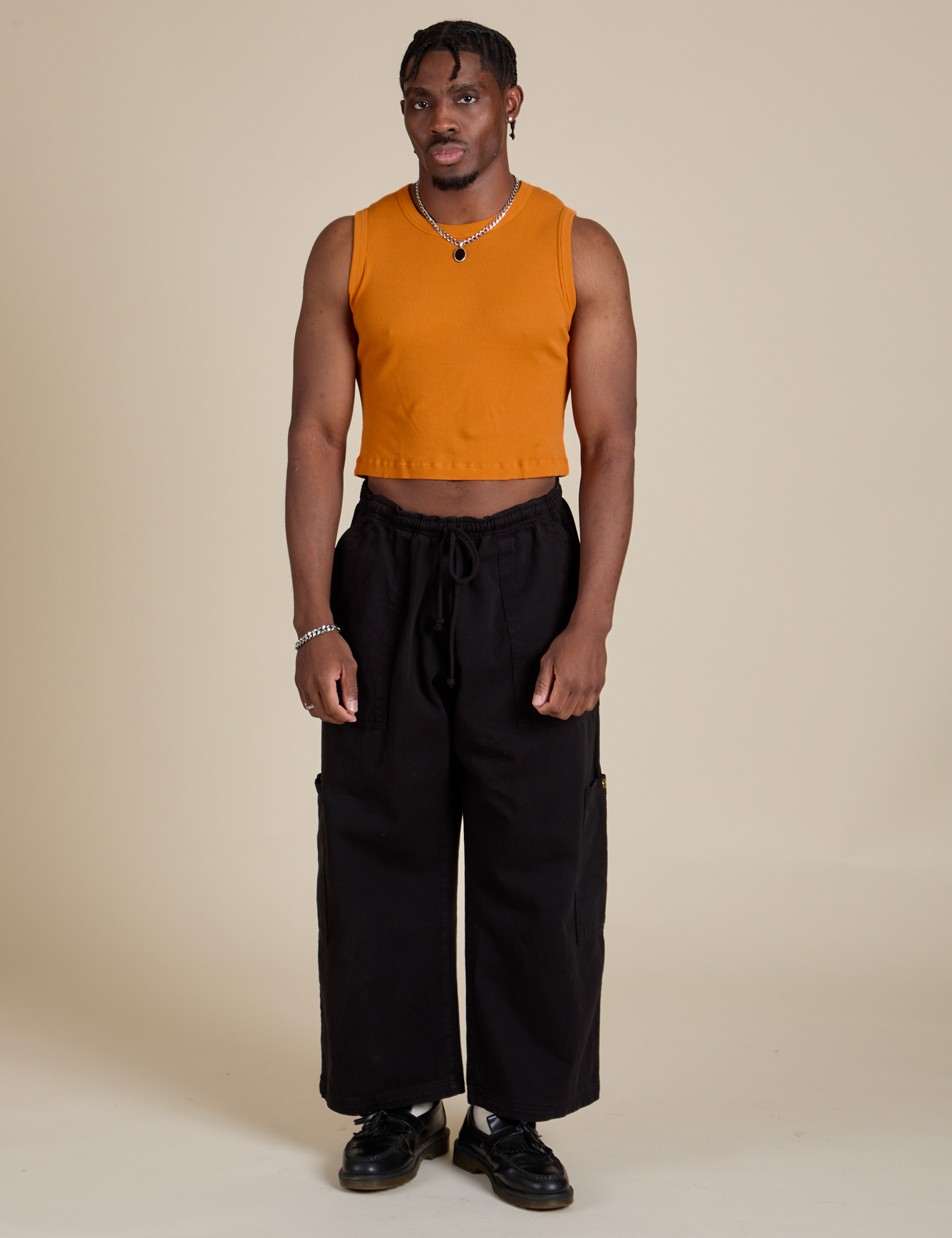 Isaac is wearing Muscle Tee in Creamsicle Orange paired with black Drop Pocket Cargo Pants