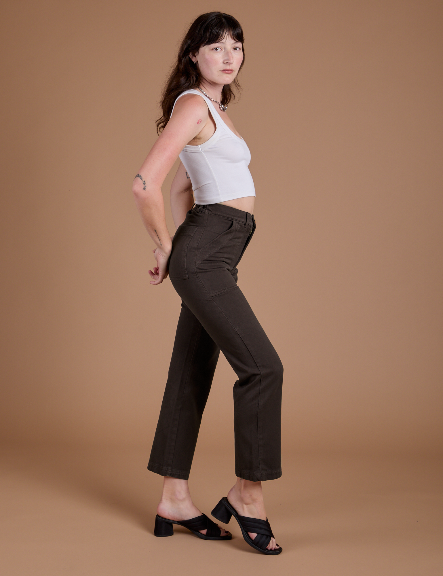 Side view of Organic Work Pants in Espresso Brown and vintage tee white Cropped Tank on Alex