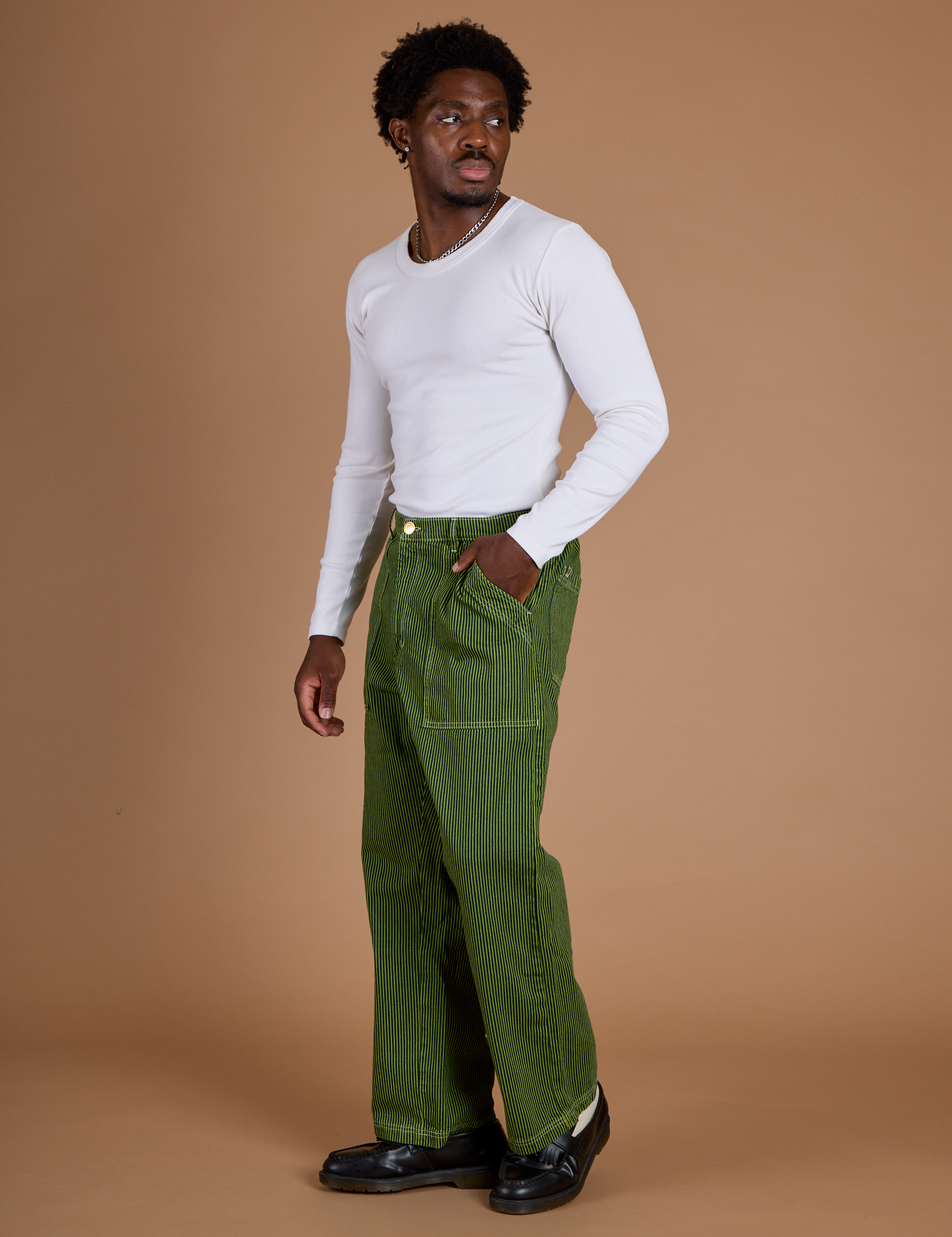 Angled front view of Railroad Denim Work Pants in Gross Green Overdye and vintage tee white Long Sleeve Baby Tee on Isaac
