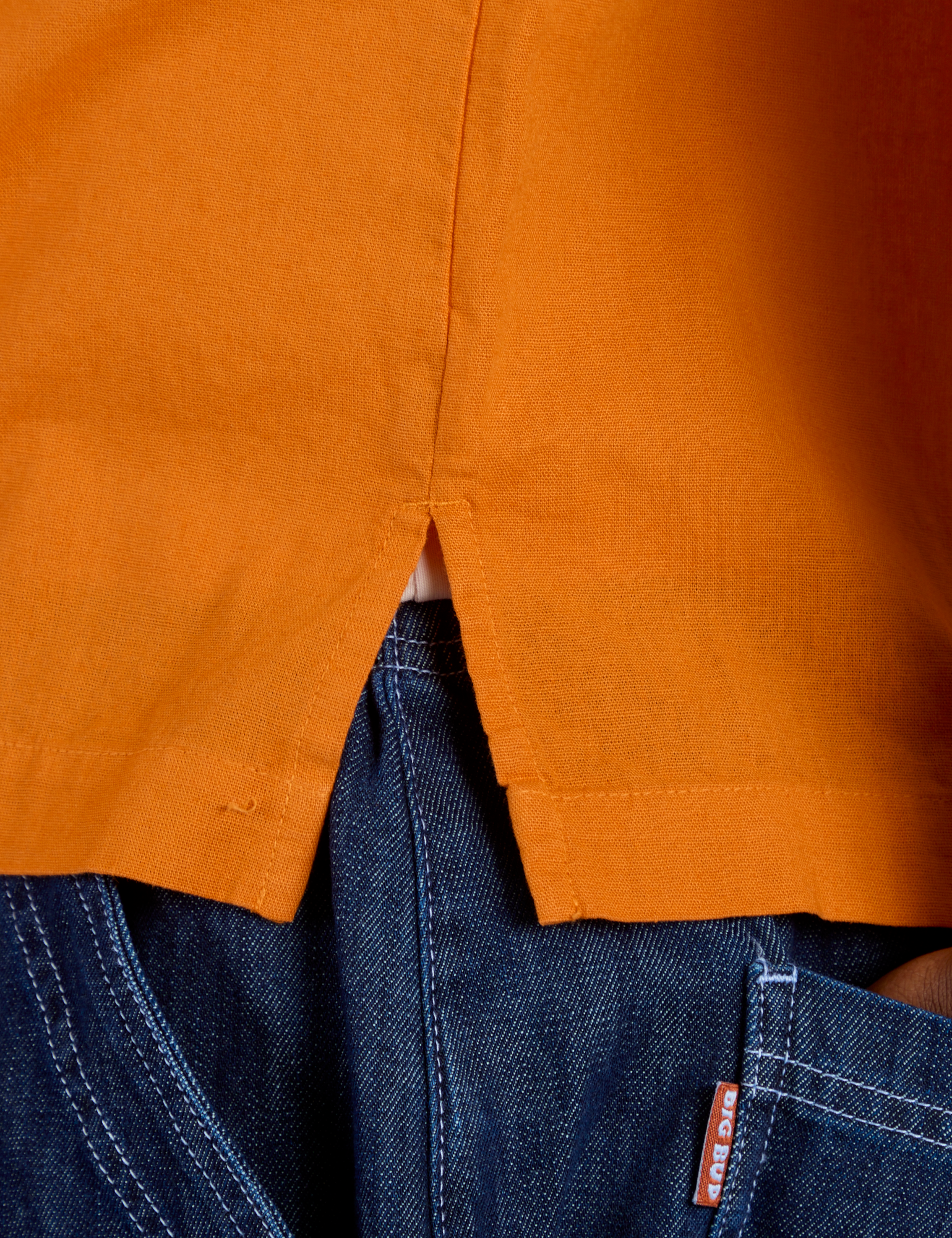 Close up of Pantry Button-Up in Creamsicle Orange side vent